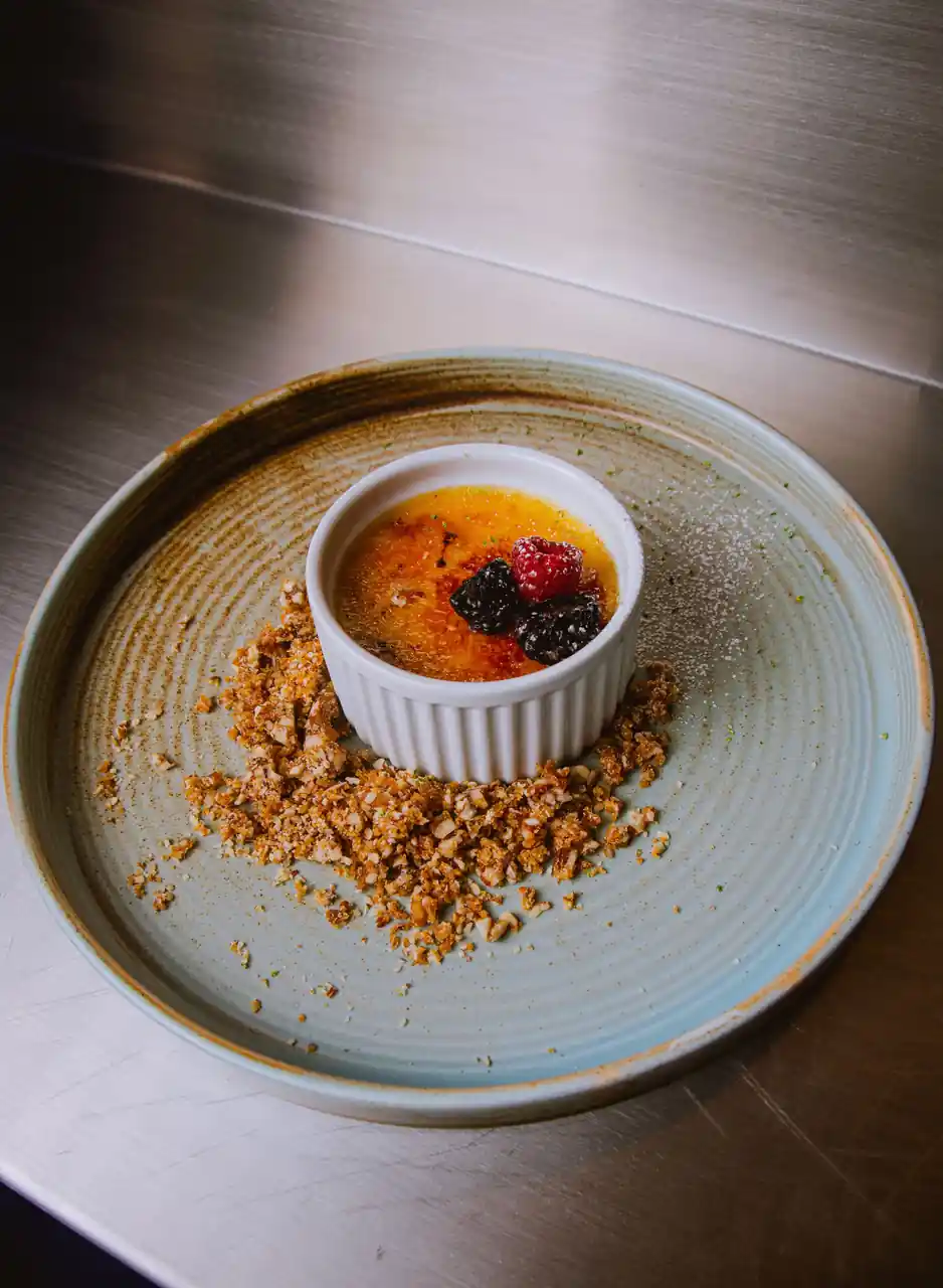 Crème brûlée with caramelized sugar crust, fresh berries and garden mint