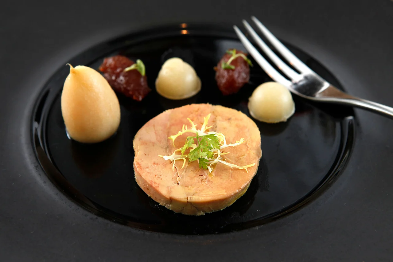 Meticulously plated French starter served on black artisanal ceramic